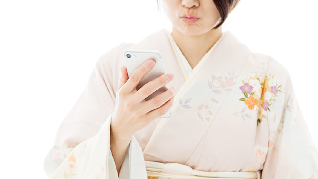 スマホを見ながら不満そうな着物の女性